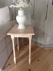 A dainty used wood table with turned legs.